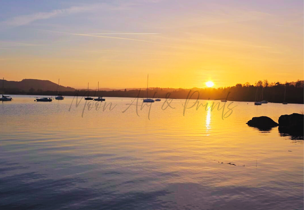 Golden sunset over Lake Windermere at Ambleside with boats resting on calm water and warm reflections across the lake
